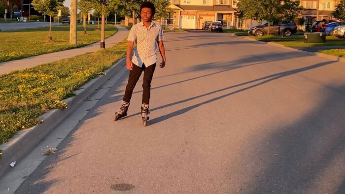 sur la route, un jeune homme s'avance en patin à roues alignées (le cinéaste).